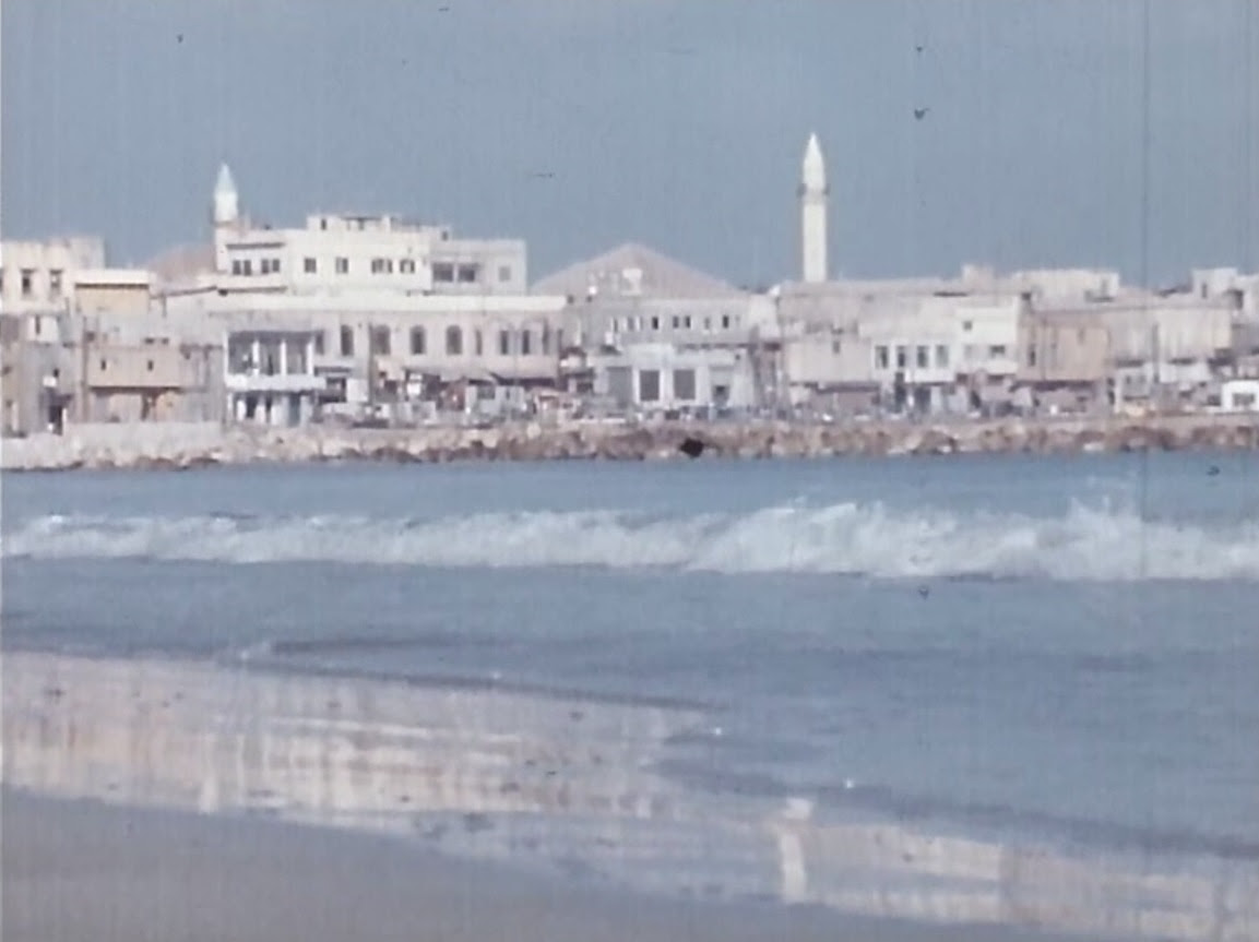 image landscape, în apropriere se vede o plajă cu mare, iar în spate sunt niște clădiri albe, de diferite înălțimi
